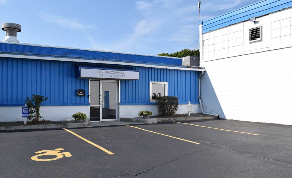 Outside view of front entrance of Archival Methods with company awning and blue and white building