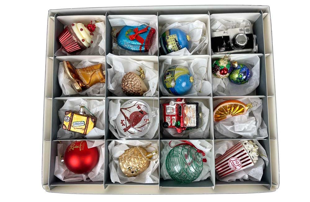 Overhead view of Archival Methods gray divided storage box with 16 compartments filled with glass Christmas ornaments laying in crumpled archival tissue for padding.