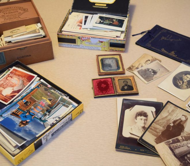 Disorganized array of old photographs laid out on a table.