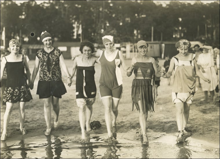Sepia toned photo of six women in old fashioned bathing costumes from around the 1920s