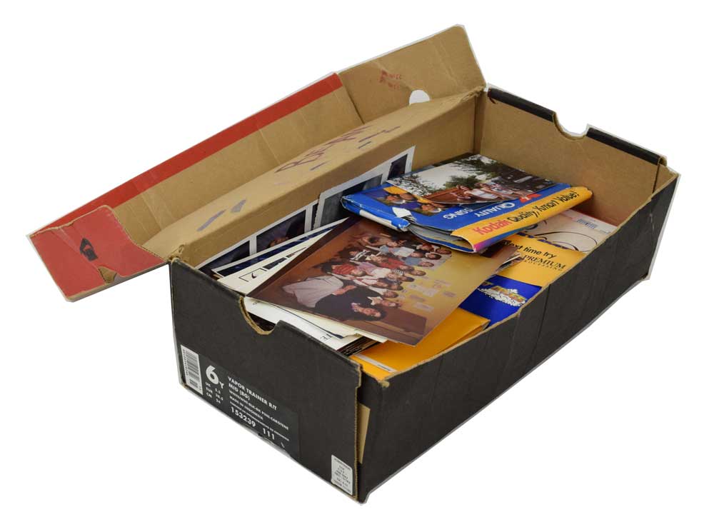 An old beat up shoebox storing photographs as an example of a bad storage environment.