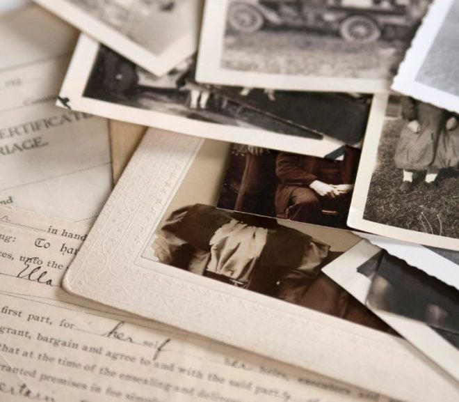 Papers and old black and white photos strewn on a flat surface