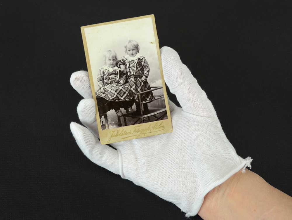 White cotton inspection gloves protect photographs and artifacts from oils and fingerprints during handling and archival care. 