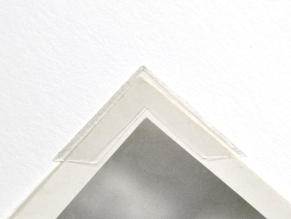Photo demonstrating acid-free mounting corners securing photos in albums and mats for safe preservation.